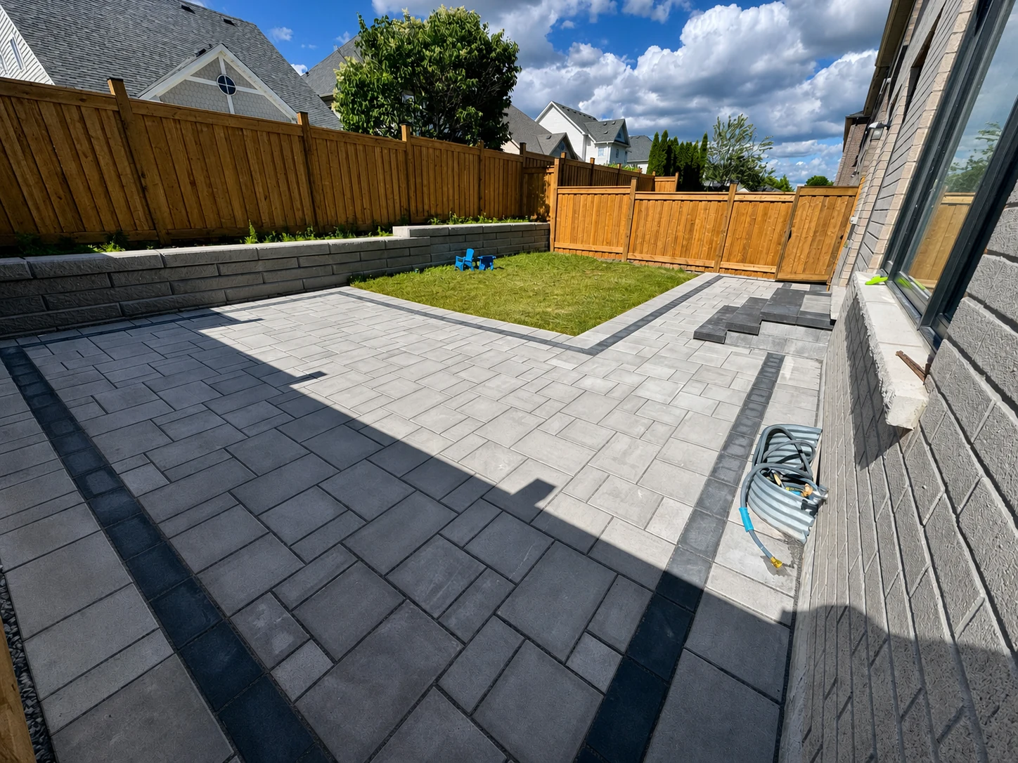 Completed interlock patio, retaining wall, lawn, and steps in a GTA backyard